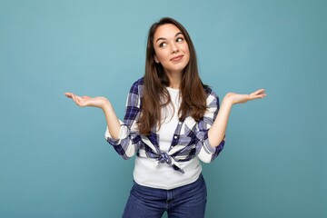 Photo of young positive happy smiling beautiful woman with sincere emotions wearing stylish clothes isolated over background with copy space and having doubts