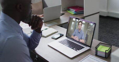 Poster - African american senior man having a video call on laptop with male office colleague at office