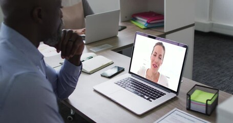 Poster - African american senior man having a video call on laptop with female office colleague at office