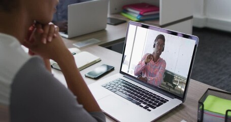 Poster - African american woman having a video conference on laptop with male office colleague at office