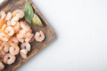 Pile of boiled peeled  shrimps, on wooden tray, on white stone  background, top view flat lay, with copy space for text