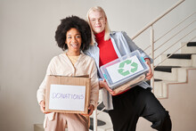 Woman And Albino Man Holding Boxes With Second-rate Clothing