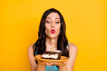 Wall Mural - Photo of adorable lady hold plate piece cake lips blow candle wear blue singlet isolated yellow color background