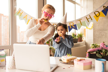 Wall Mural - Mother celebrating birthday of her little daughter while speaking with friends