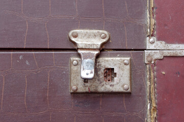 close up of old metal silver fastener on a large vintage brown closed suitcase 