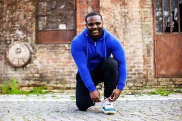 Wall Mural - Sporty man is tying shoelace outdoor.