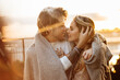 © shunevich - Portrait of happy beautiful couple at the sunset, cuddling in cozy blanket. Charming loving blond man hugging attractive woman, enjoying tenderness, spend time together, romantic date concept