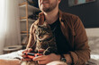 © Yakobchuk Olena - Cat sitting at the laps of his owner and looking at the tv while man is playing