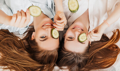 Wall Mural - two girls make homemade face and hair beauty masks. cucumbers for the freshness of the skin around t