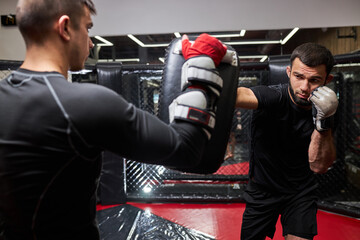 Two sporty men boxers exercising kick boxing in ring at health club or gym, practice fighting, mma, in action. sport, fintess, kickboxing concept