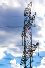 High voltage electric towers in a row with cloudy blue sky background