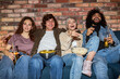 © alfa27 - young friends watching tv, comedy show or movie, eating snacks and drinking beverage, sitting on cozy couch at home, diverse guys and ladies enjoying free time, weekend together