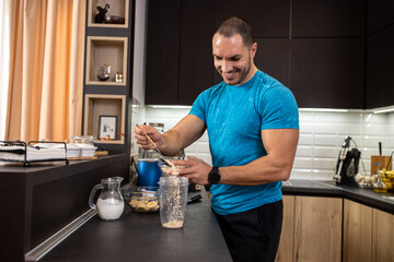 Young muscular man preparing ingredients for a tasty shake in the kitchen