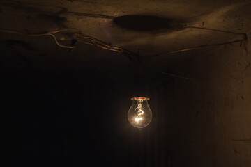 The old incandescent lamp with a tungsten filament. Light bulb close-up isolated black background.