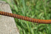 Long Iron Piece Of Rebar In Red Rust On Gray Green Background Outdoors