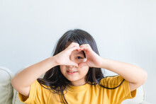 Healthy Eyes And Vision.Portrait Happy Asian Kid Child Holding Heart Shaped Hands On Eyes.Smiling Girl With Healthy Skin Showing Love Sign. Eye Care.Carotene Vitamin.Focus, Optician Doctor, Optical.