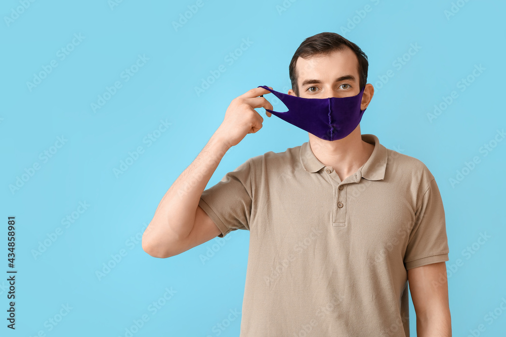 Young man wearing medical mask on color background