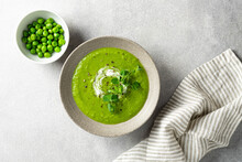 Green Pea Soup In A Ceramic Bowl On Gray Concrete Background, Top View