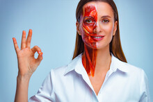 Happy Young Woman With Half Of Face With Muscles Structure Under Skin With Ok Sign. Model For Medical Training On A Light Background.