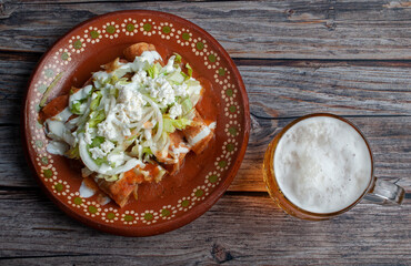 flat lay photography, potato and beef fried tacos, in a mexican mud plate with cream lettuce tomato salsa and onions with lemon on top with a jar of cold beer on the side. Tacos dorados concept.