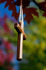 Sticker - Christian cross hanging on a tree branch with red leaves. Autum.