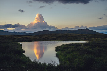 Wall Mural - scenic sunset landscape with yellow big cloud in form of explosion above mountain lake. awesome gian