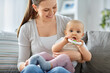 family, motherhood and people concept - happy smiling mother and little baby playing with teething toy or rattle at home