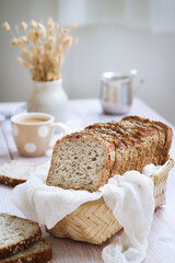 A loaf of multi grains and cereals healthy flourless bread with low calories and vegan in a bamboo basket, cup of coffee in background. High in proteins. Paleo and ketogenic diet 