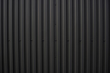 Black Corrugated Iron Sheet Used As A Facade Of A Warehouse Or Factory. Texture Of A Seamless Corrugated Zinc Sheet Metal Aluminum Facade. Architecture. Metal Texture.