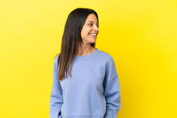 Wall Mural - Young caucasian woman isolated on yellow background looking side