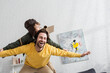 © LIGHTFIELD STUDIOS - Low angle view of happy dad playing with boy in aviator costume