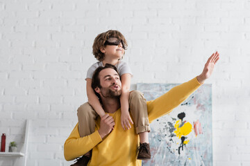 Wall Mural - Father playing with son in aviator goggles