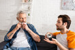 © LIGHTFIELD STUDIOS - Man talking near father drinking coffee at home