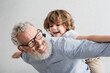 © LIGHTFIELD STUDIOS - Cheerful granddad playing with blurred grandson at home