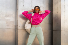 Playful Woman Having Fun In Neon  Pink Jacket  Over Grey Metallic Urban Wall.  Fashionable  Sportive  Outfit.