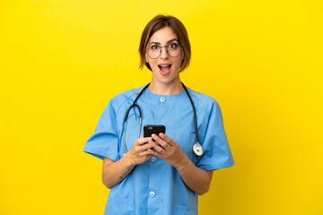 Surgeon doctor woman isolated on yellow background surprised and sending a message