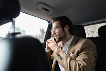 Wall Mural - businessman in suit talking on smartphone and looking at car window