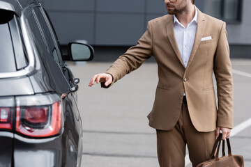 partial view of man in beige suit and glasses reaching car door