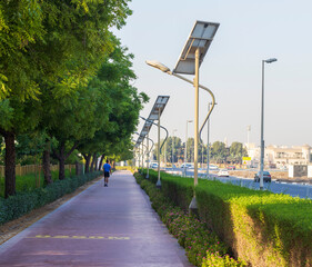 Wall Mural - Dubai, UAE - 05.21.2021 - Middle aged man walking on jogging track in Nad Al Hamar park, early in the morning. Lamp post powered by solar panels can be seen in the picture. Outdoors