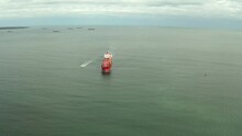 Aerial View Of Cargo Ship Calling Into The Port Under The Guide Of Tugboat.