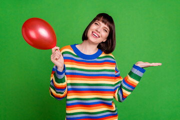 Sticker - Photo of cheerful nice young woman smile hold hands empty space balloon isolated on green color background