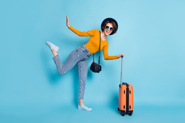 Poster - Full size profile photo of optimistic brunette short hairdo lady stand with bag fly wear shirt jeans sneakers isolated on blue color background