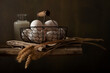 Still life in rustic style. Composition with basket of eggs, bunch of wheat ears on wooden table.
