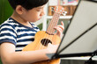 © myboys.me - Cute Asian little boy playing and practicing ukulele skills with focus and concentration at home. Acoustic Music instrument, Child brain development activity, Homeschool and music therapy concept.