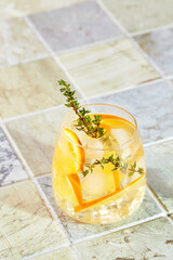 Wall Mural - Refreshing cocktail with ice, orange and thyme. Refreshing summer homemade alcoholic or non-alcoholic cocktail or mocktail, or Detox infused flavored water