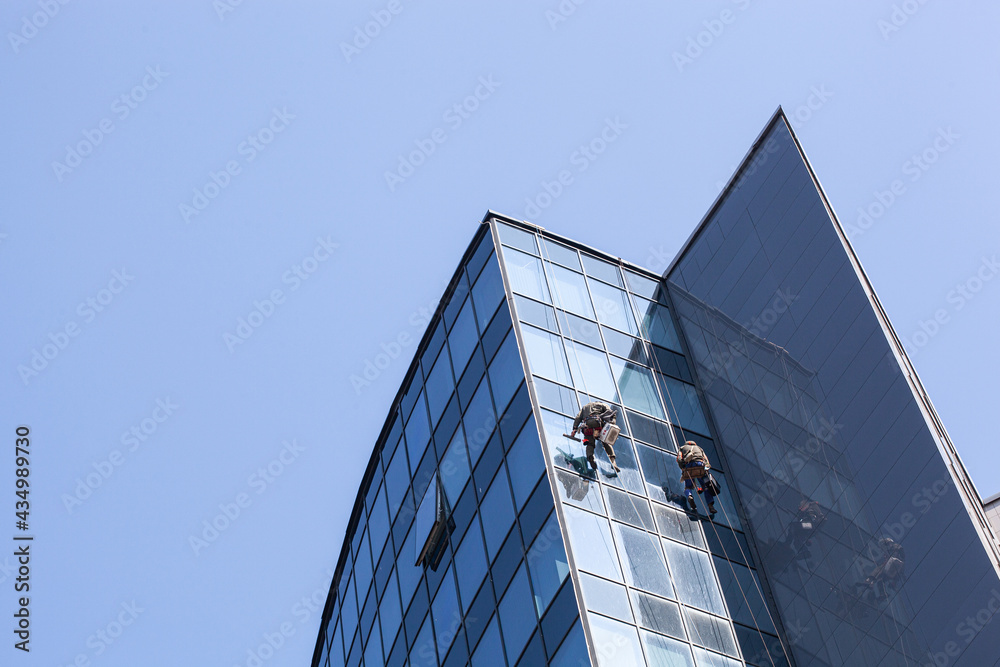 Climbers clean windows from the outside of a multi-storey building の ...