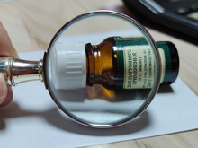The Inscription On The Bottle And The Magnifying Glass. Enlargement Of Letters. Small Print, Green Tone. Shallow Depth Of Field, Poor Vision After 40.