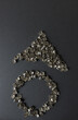 old, worn, recycled square pyramidal metallic studs or spikes arranged in the shape of a circle and triangle on a dark board w/low, raking light - photo from above in a flay lay composition
