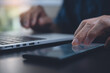 © tippapatt - Close up of man hand using mobile phone and finger touching on phone screen and working on laptop computer