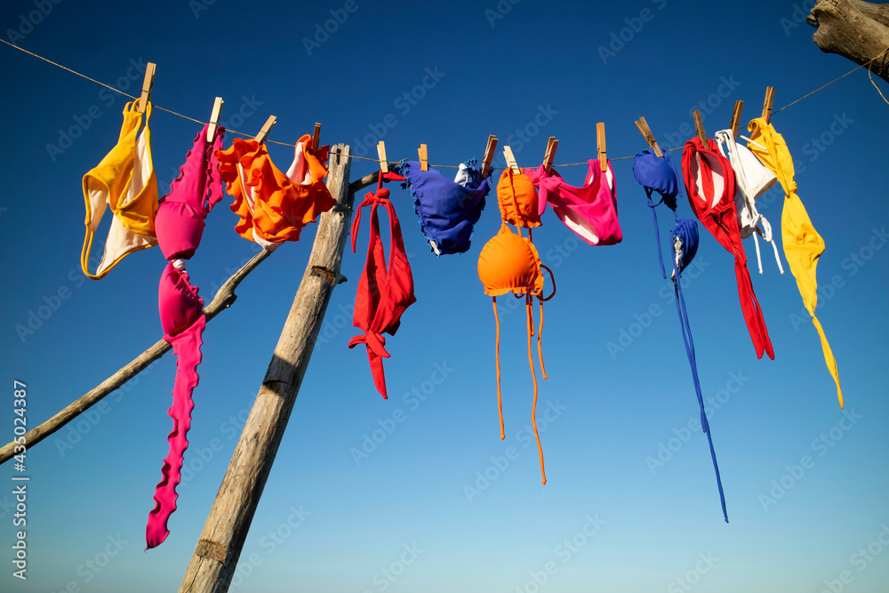 Female swimwear hanging in the sun to dry - obrazy, fototapety, plakaty 